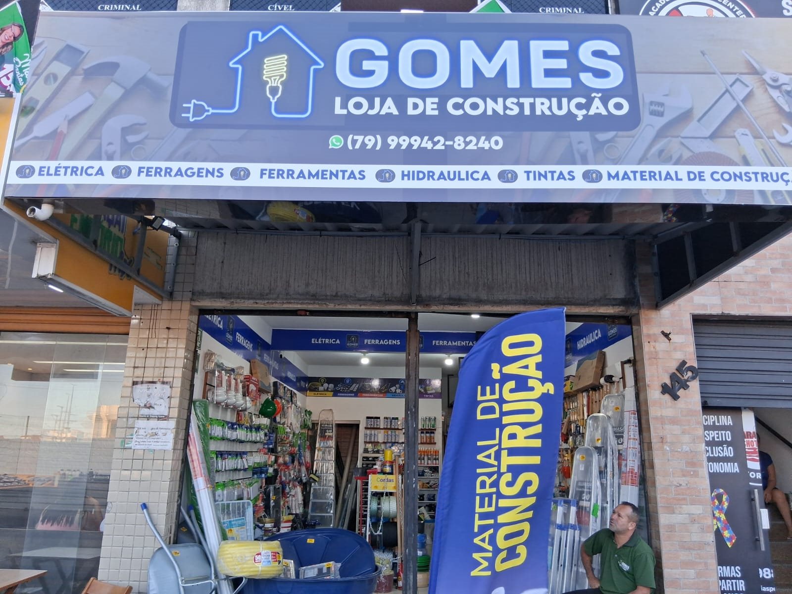 Entrada da Gomes com sua placa de identificação e materiais na vitrine